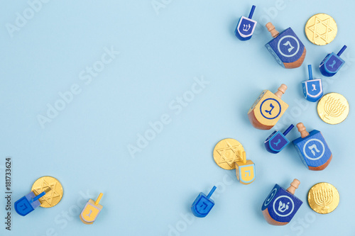 Blue background with multicolor dreidels and chocolate coins. Hanukkah and judaic holiday concept.
