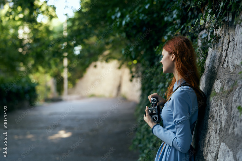Young beautiful woman in a blue dress is holding a camera on the street Young beautiful woman in a blue dress is holding a camera on the street