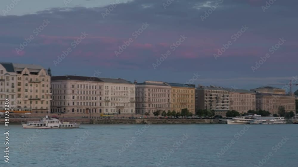 Pan across Danube River from Chain Bridge to Hungarian Parliament during evening twilight, Budapest. A small tour boat is in shot Pan across Danube River from Chain Bridge to Hungarian Parliament during evening twilight, Budapest. A small tour boat is in shot
