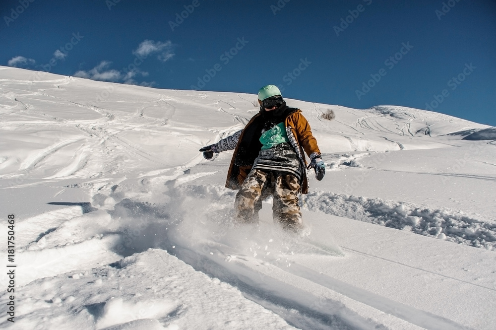 Back view of snowboarder in sportswear riding down the mountain