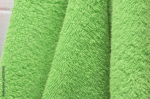 Wavy dry bath towels of color green hanging in bathroom close-up