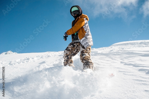 Portrait of snowboarder in sportswear standing on the snow hill