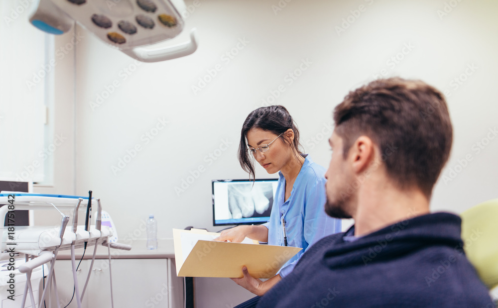 Dentist examining the reports of patient in clinic Dentist examining the reports of patient in clinic
