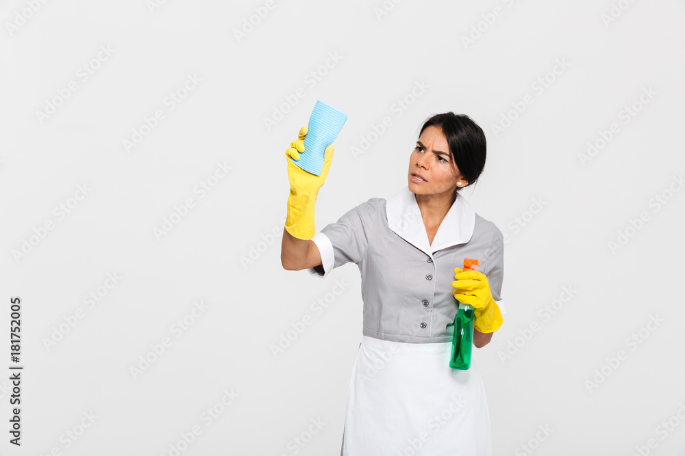 Young concentrated maid in uniform cleaning window with rag Young concentrated maid in uniform cleaning window with rag