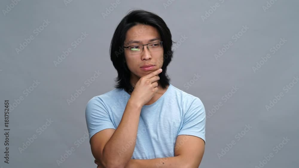 Handsome concentrated young asian man thinking something isolated