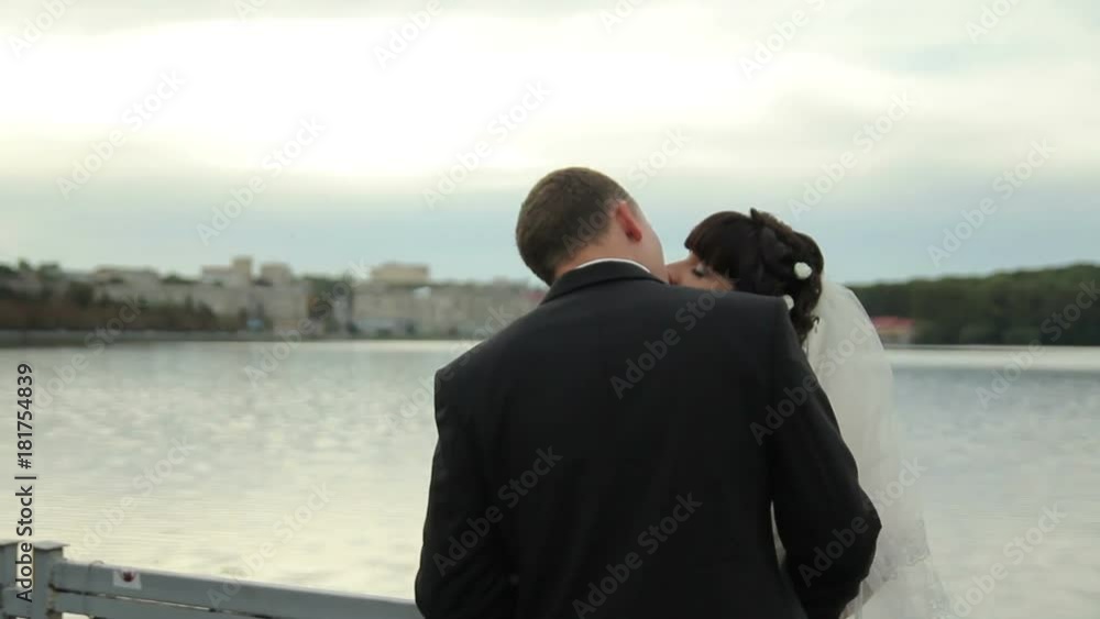 bride and groom stand near the blue lake . Beautiful newlyweds in love on a lake background. Portrait of happy newlywed couple in tenderness love bride and groom stand near the blue lake . Beautiful newlyweds in love on a lake background. Portrait of happy newlywed couple in tenderness love