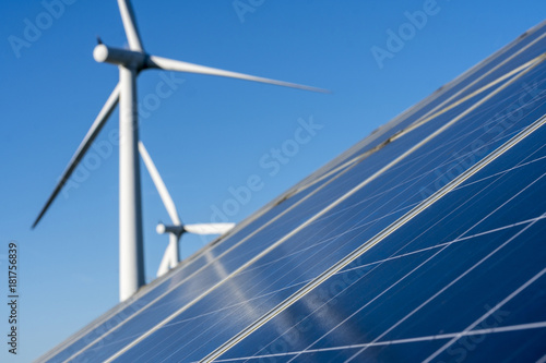 Solar panels and wind turbine on a clear blue sky day