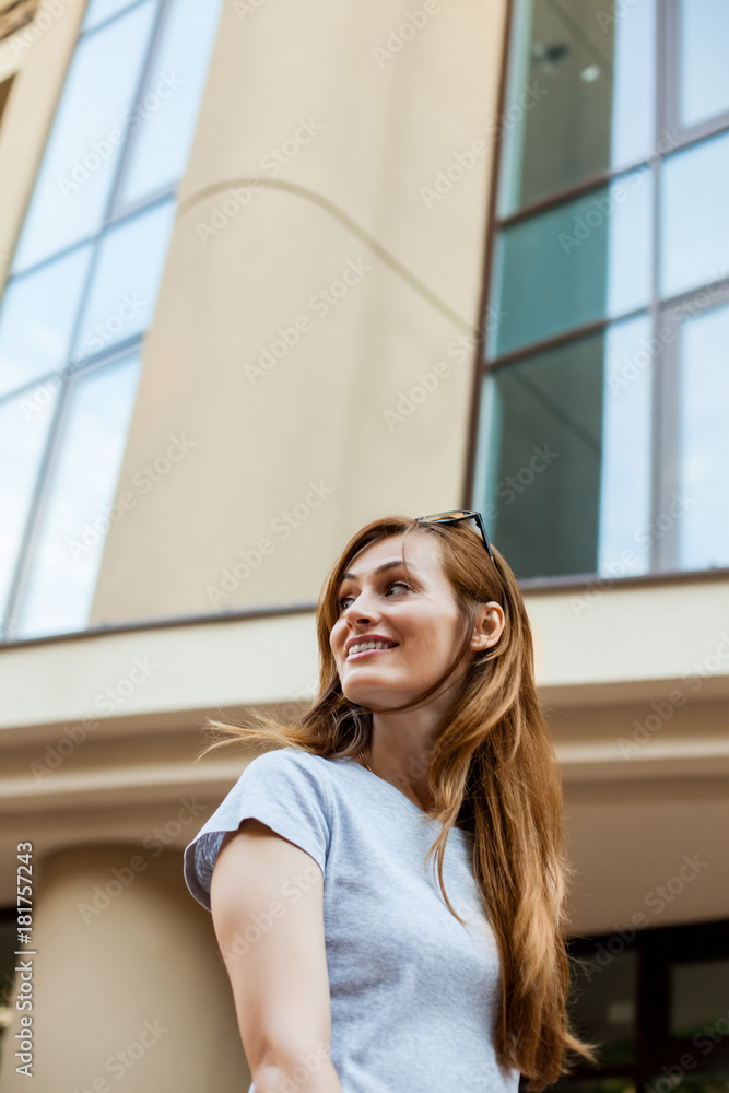chearfull redhead hipster teenager in a gray shirt smiling and walking in the street. Concept of modern freedom hipster human, close up portrait