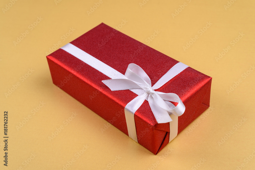 Red gift box with ribbon and bow on golden background, copy space. Holiday greeting card. Mothers day, birthday, Women's Day, mum's day, Valentine's day, Christmas, Wedding, Anniversary, 8 March Red gift box with ribbon and bow on golden background, copy space. Holiday greeting card. Mothers day, birthday, Women's Day, mum's day, Valentine's day, Christmas, Wedding, Anniversary, 8 March
