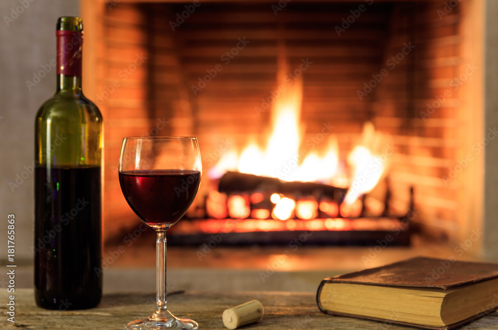 Red wine and a book on burning fireplace background Red wine and a book on burning fireplace background