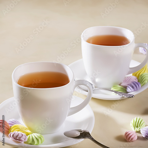 two white cups of tea with colorful meringue
