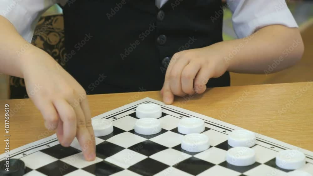 Intellectual games in kindergarten indoors. Little unidentified boy in formal attire plays checkers. Close-up Intellectual games in kindergarten indoors. Little unidentified boy in formal attire plays checkers. Close-up