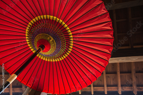 Traditional Japanese umbrella on a wooden house wall background.