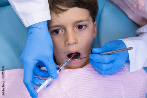 Dentist holding medical equipment while examining boy