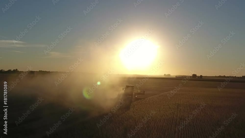 Combine harvesting a field of soybeans as sunset in midwest United States Combine harvesting a field of soybeans as sunset in midwest United States