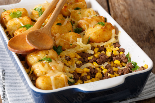 Homemade casserole of Tater Tots with minced beef, corn and cheese close-up in a baking dish. horizontal