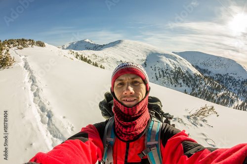 Selfi male traveler with a backpack in the winter mountains