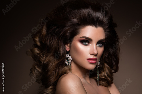 Glamour portrait of beautiful girl model with makeup and romantic hairstyle. Fashion shiny highlighter on skin, sexy gloss lips make-up and dark eyebrows.