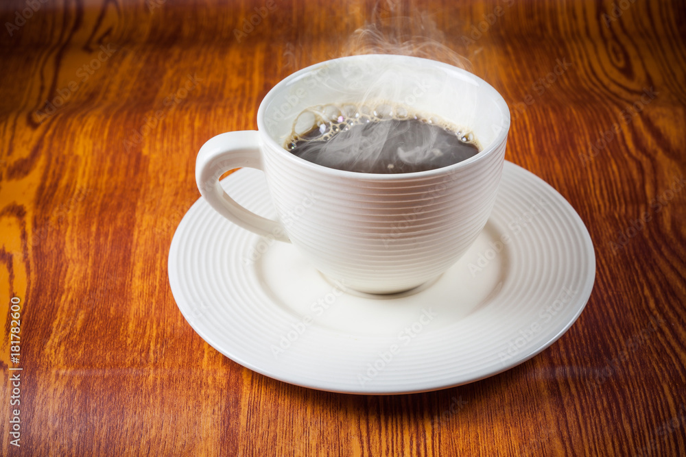Fototapeta premium Hot coffee in white cup on wooden floor.