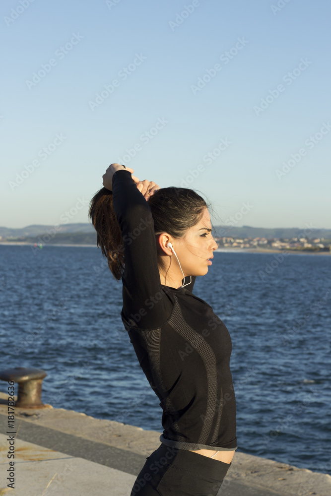 Female runner making a ponytail preparing for jogging looking to the city bay