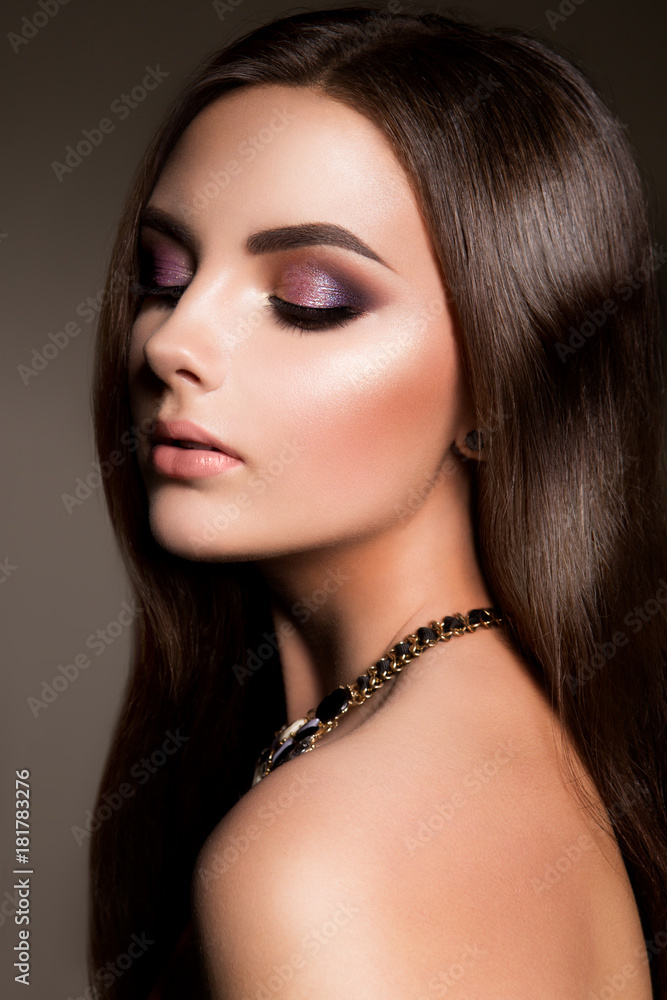 Glamour portrait of beautiful girl model with makeup and romantic hairstyle. Fashion shiny highlighter on skin, sexy gloss lips make-up and dark eyebrows.