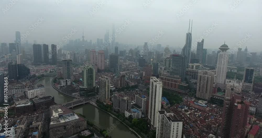 SHANGHAI, CHINA – JUNE 2016 : Aerial shot in central Shanghai on a misty day with skyscrapers, canal and Shanghai Tower in view SHANGHAI, CHINA – JUNE 2016 : Aerial shot in central Shanghai on a misty day with skyscrapers, canal and Shanghai Tower in view