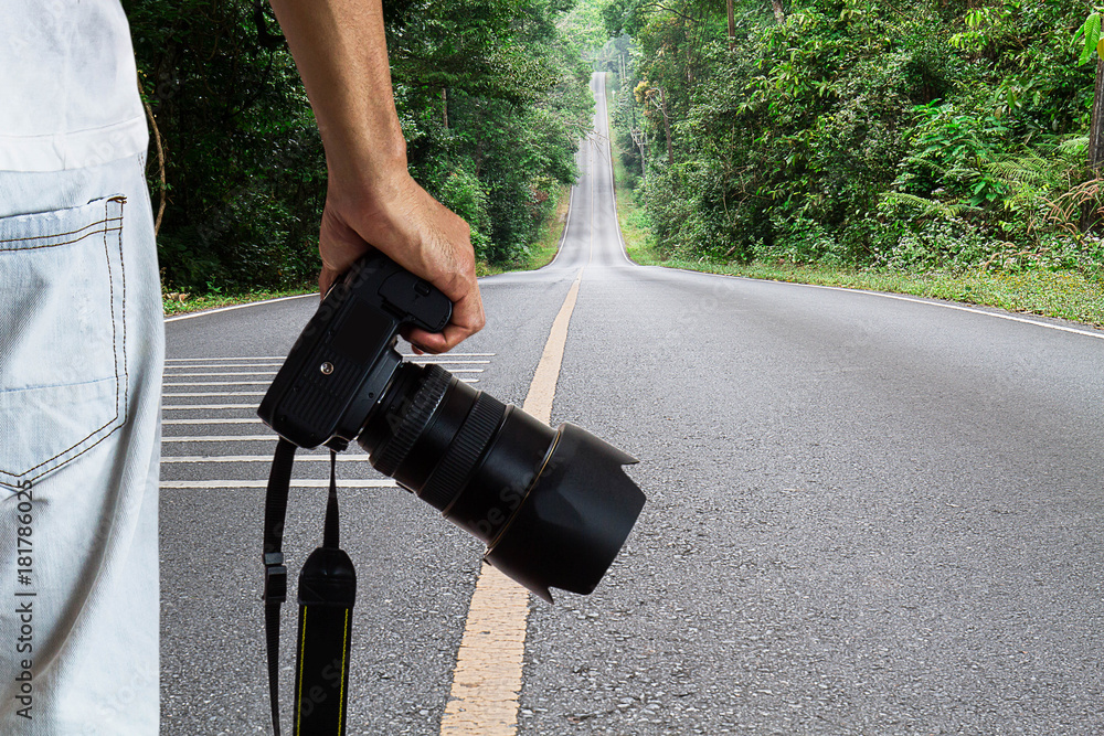 Man holding dslr digital camera on blurred straight road in national park  background, photography hobby concept Stock Photo | Adobe Stock
