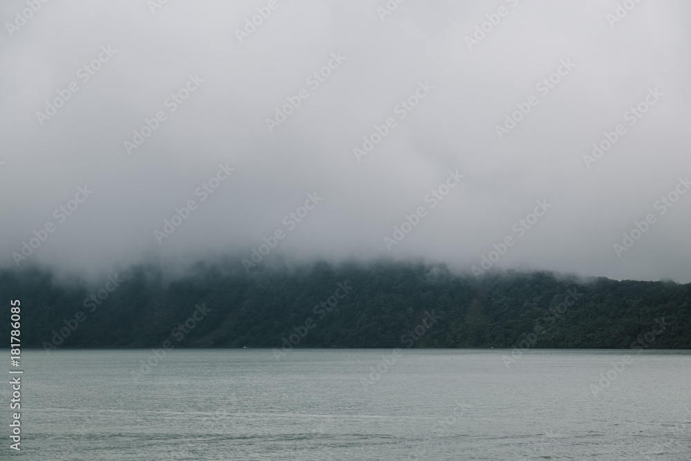 Fototapeta premium Low clouds over mountain near lake. Tranquil scene landscape