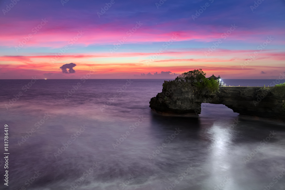 Pura Batu Bolong at dusk - temple on the rock near Tanah Lot in Bali, Indonesia. Pink sunset