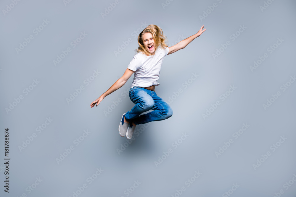I'm trying to fly! Screaming smiling excited mad handsome hipster is celebrating and jumping up, isolated on grey background
