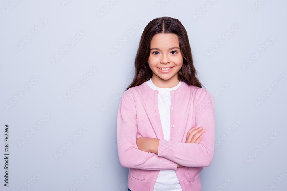 Close up portrait of adorable little sweet happy girl made her hands crossed while standing over grey background Close up portrait of adorable little sweet happy girl made her hands crossed while standing over grey background