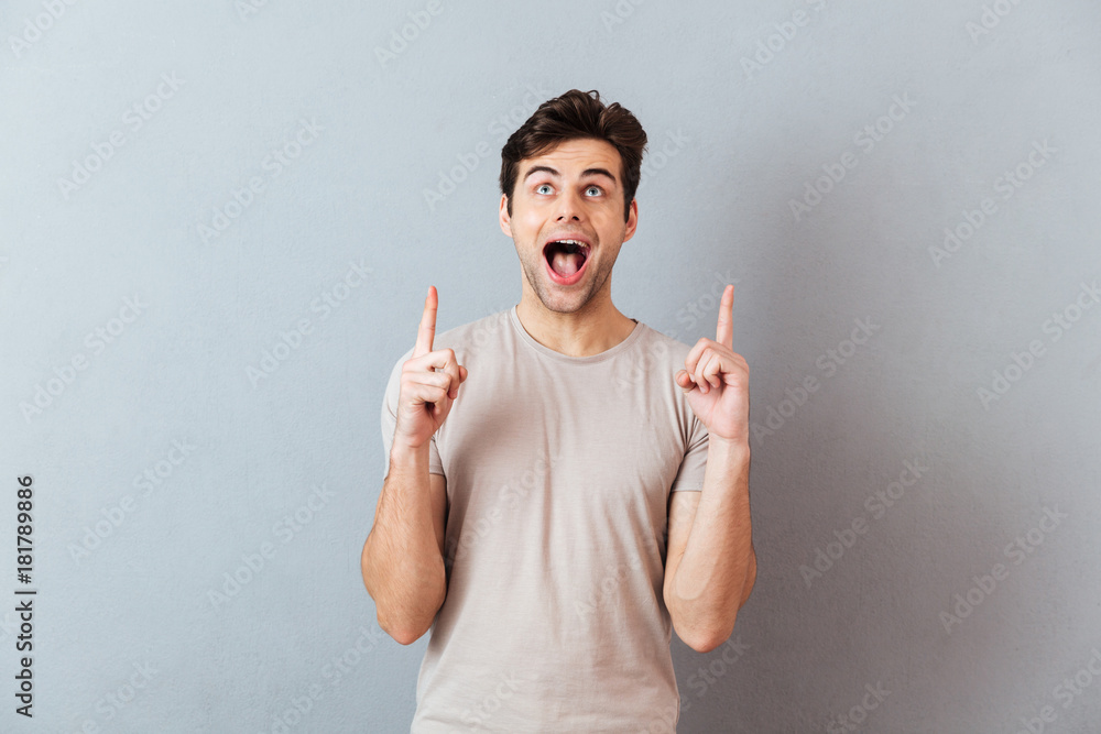 Portrait of a cheerful happy man pointing fingers up Portrait of a cheerful happy man pointing fingers up