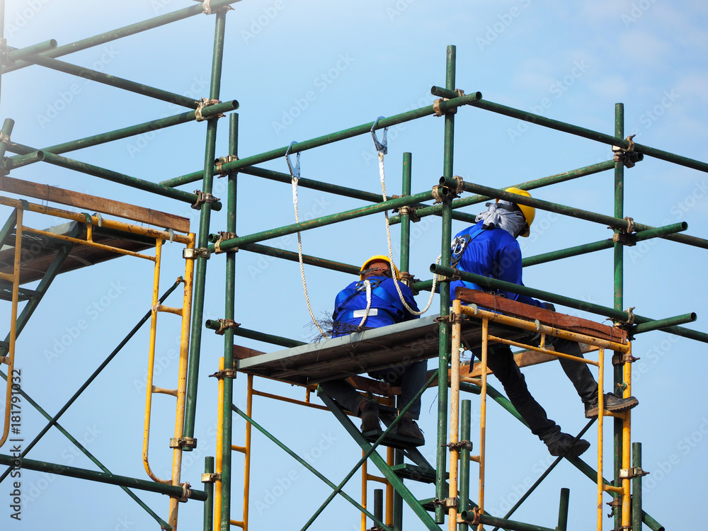 Construction workers working on scaffolding, Man Working on the Working at height with blue sky at construction site