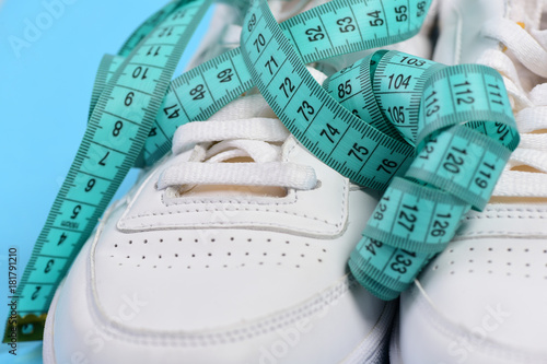 Sneakers with measuring tape on cyan background.