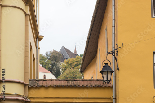 View  of the old city in the opening between the housesin  Sighisoara city in Romania photo