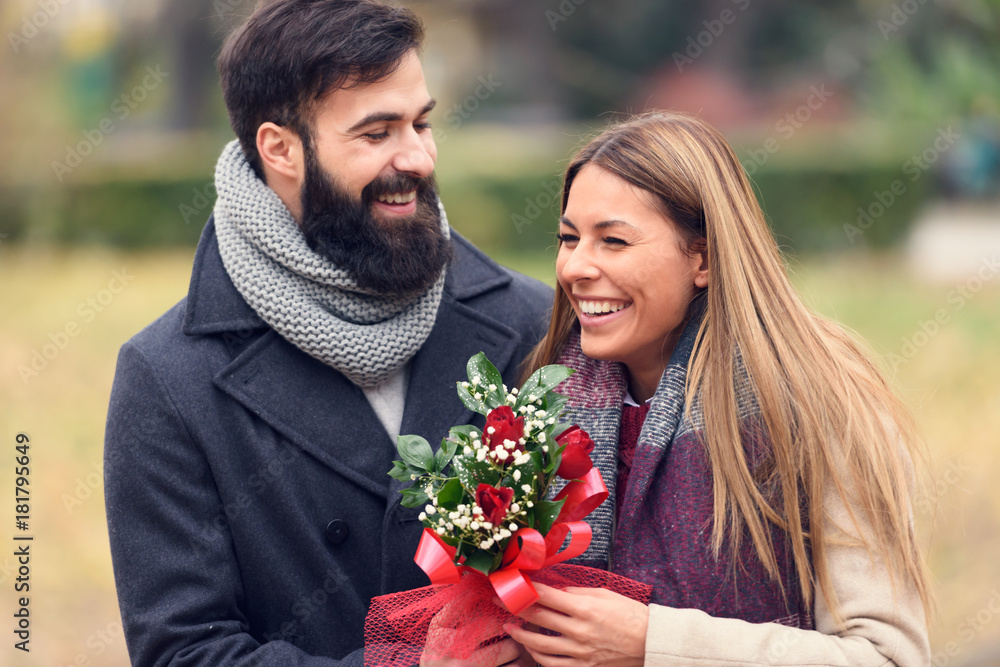 Smiling Romantic Valentines-Day Couple with Flowers in Park Smiling Romantic Valentines-Day Couple with Flowers in Park