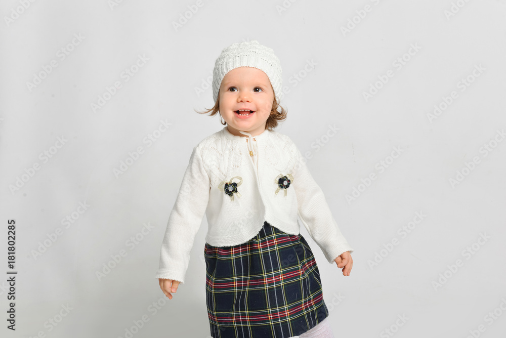 Little girl in a cap and sweater. Isolated on a gray background. Little girl in a cap and sweater. Isolated on a gray background.