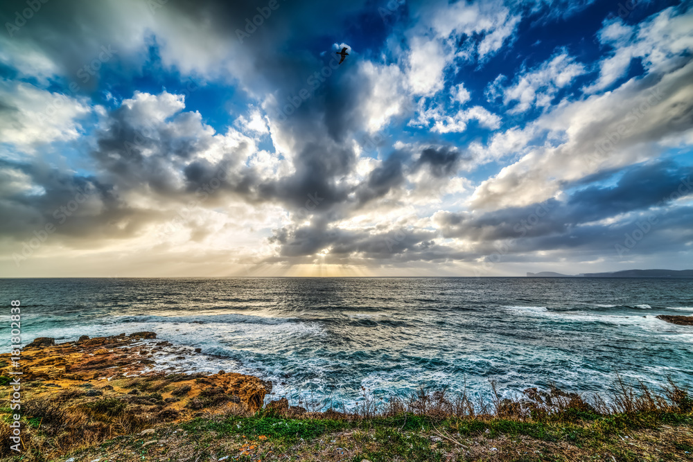Obraz premium Dramatic sky over Alghero rocky shore