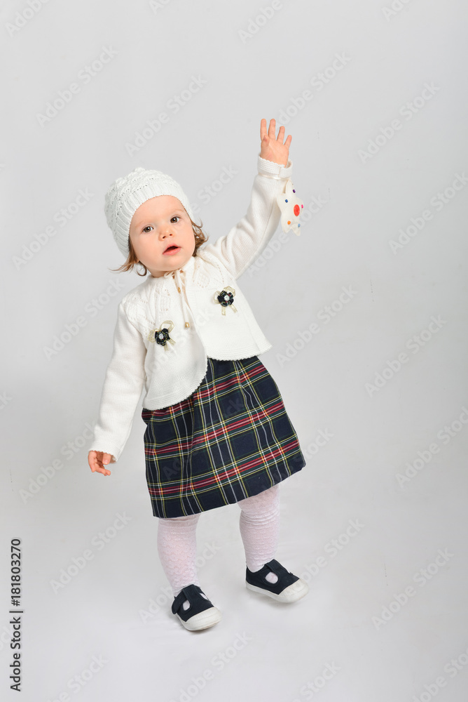 Little girl in a cap and sweater. Isolated on a gray background. Little girl in a cap and sweater. Isolated on a gray background.