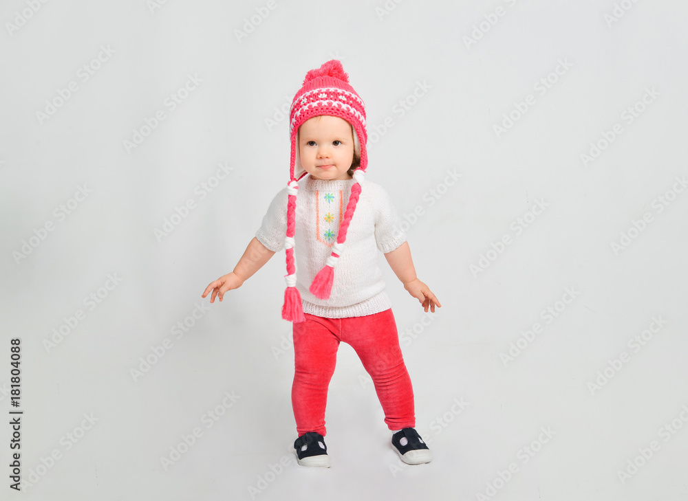 Little girl in a cap and sweater. Isolated on a gray background. Little girl in a cap and sweater. Isolated on a gray background.