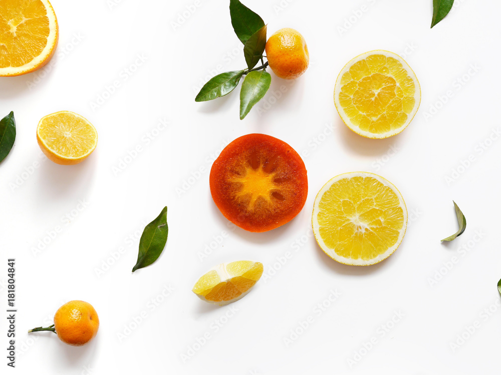 Creative flat layout of fruit, top view. Sliced orange, lemon, persimmon, tangerine, green leaves isolated on white background. Food wallpaper, composition pattern of fresh fruits.