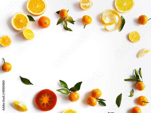 Frame made of fruits.Creative flat layout of fruit  top view.Sliced orange  lemon  persimmon  tangerine  green leaves isolated on white background. Food wallpaper  composition pattern of fresh fruits.