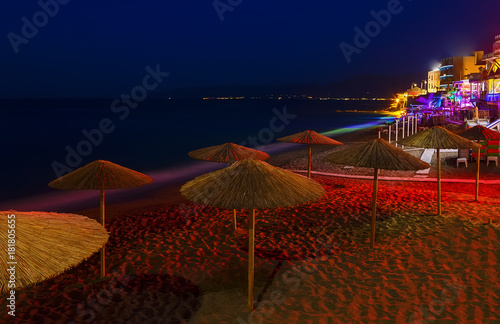 Beautiful evening with night shore with a beach and umbrellas and highlighted with bright colorsin Hersonissos bay Crete, Greece photo