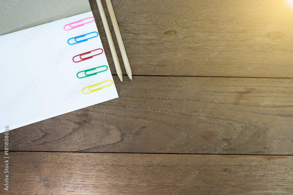 Paper clips on notebook with pencils on wooden table. Concept school supplies. Paper clips on notebook with pencils on wooden table. Concept school supplies.