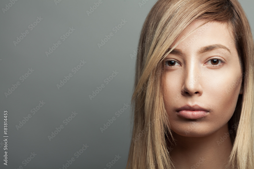 Pure beauty concept. Portrait of a beautiful fashion model with blonde long hair, natural make-up posing over gray background. Close up. Copy-space. Studio shot Pure beauty concept. Portrait of a beautiful fashion model with blonde long hair, natural make-up posing over gray background. Close up. Copy-space. Studio shot