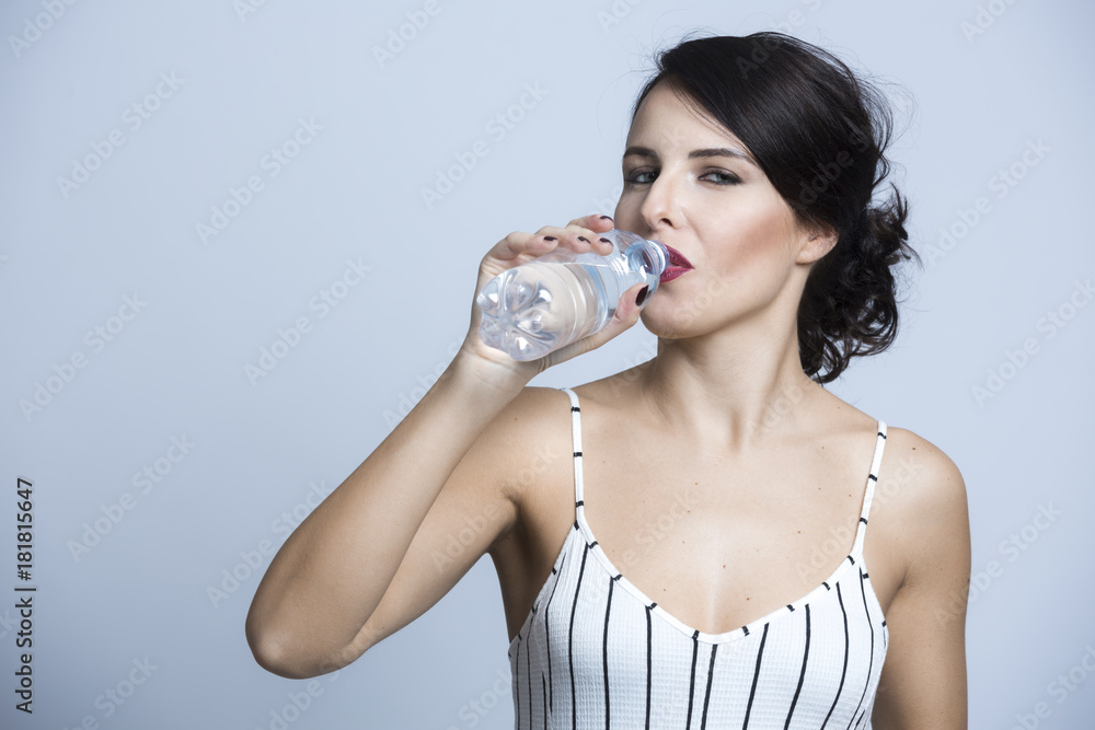 Bellissima beve da una bottiglia d'acqua - sfondo celeste chiaro Bellissima beve da una bottiglia d'acqua - sfondo celeste chiaro