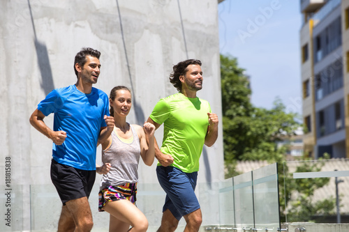 Two young men and woman running in urban enviroment
