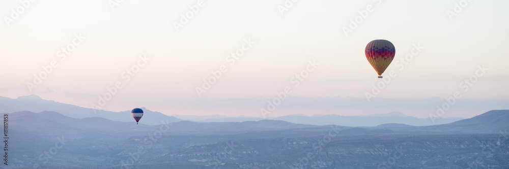 Hot air balloons over mountain landscape in Cappadocia, Goreme National Park, Turkey.