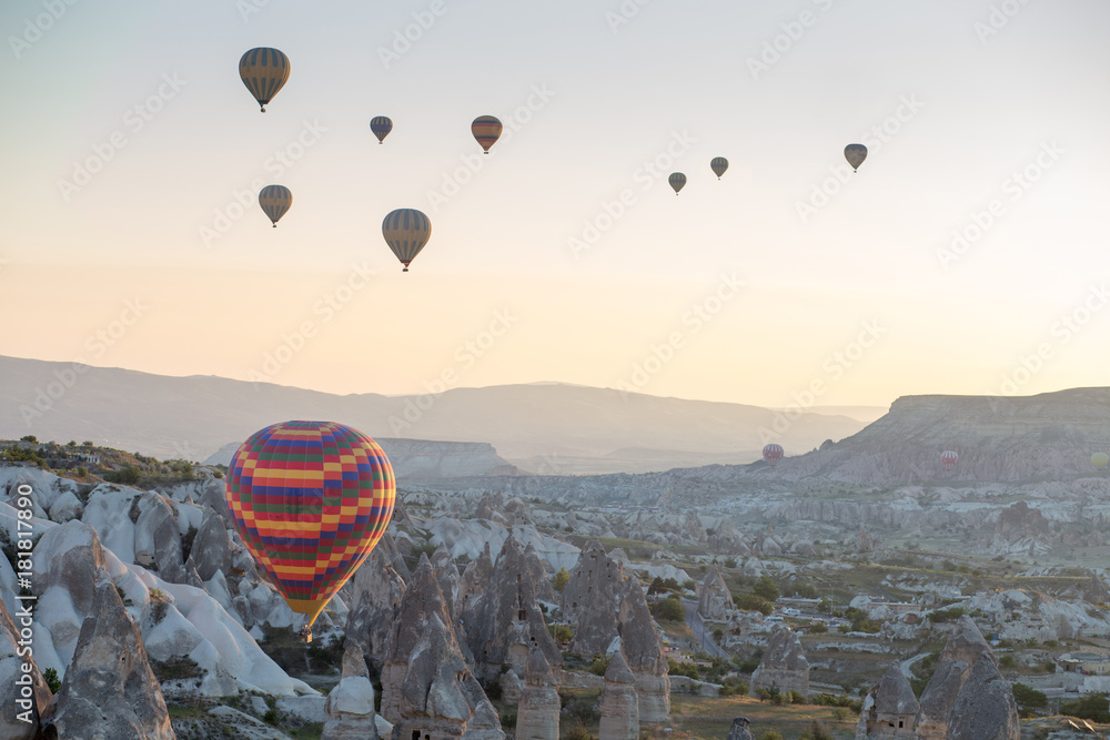 Hot air balloons over mountain landscape in Cappadocia, Goreme National Park, Turkey.