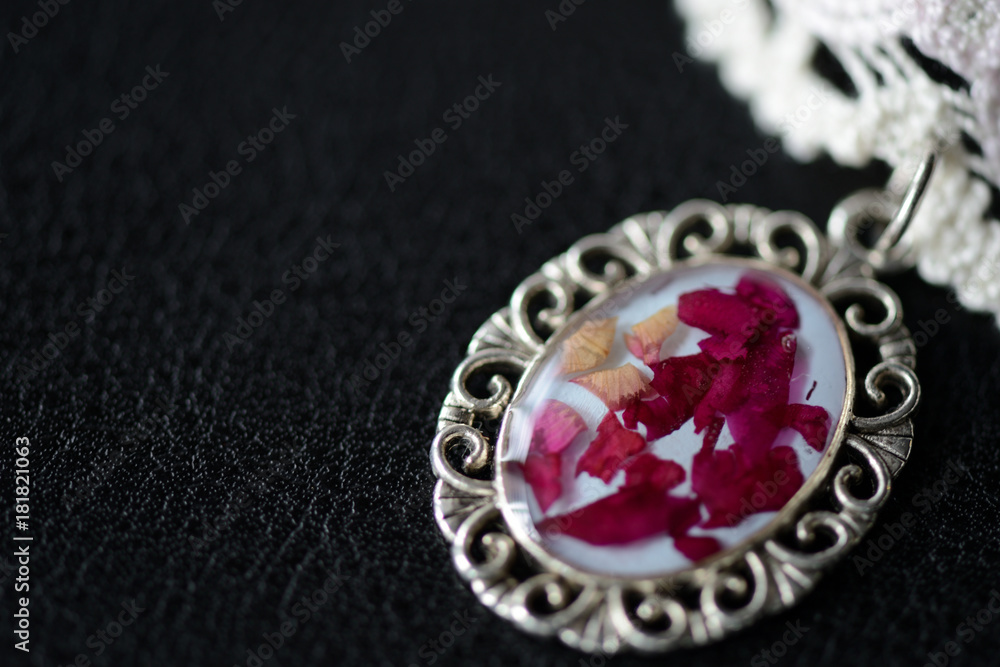 Beige lace choker with a rose petals pendant on a dark background Beige lace choker with a rose petals pendant on a dark background